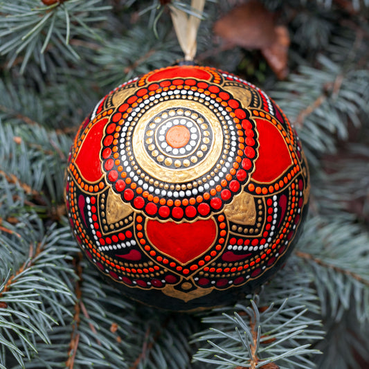 Close-up view of a red Christmas ornament with hand-painted mandala design.