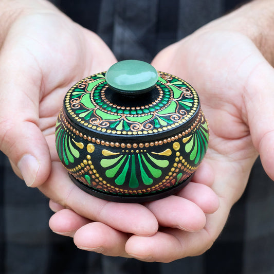 Wooden round hand-painted box in green tones, man holding the box in open hands