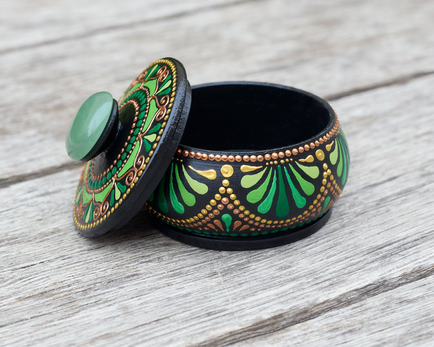 Decorative wooden hand-painted green box with natural stone on the lid on a wooden surface