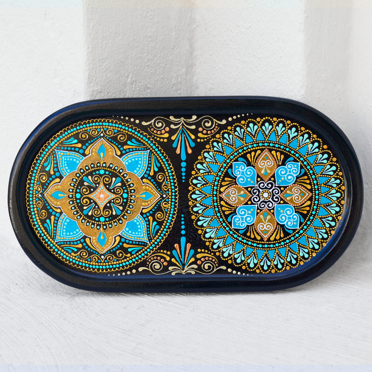 Small oval wooden tray hand-painted with mandala. Moroccan tray for coffee table. Front view on the white wall background.