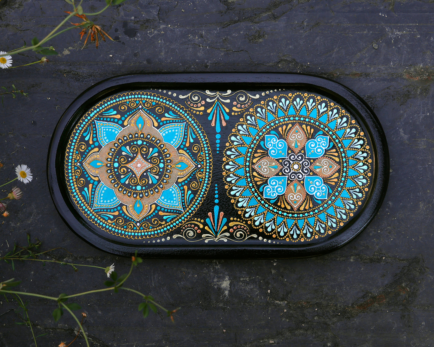 Small oval wooden tray hand-painted with mandala. Moroccan tray for coffee table. Top view on the dark stone background.