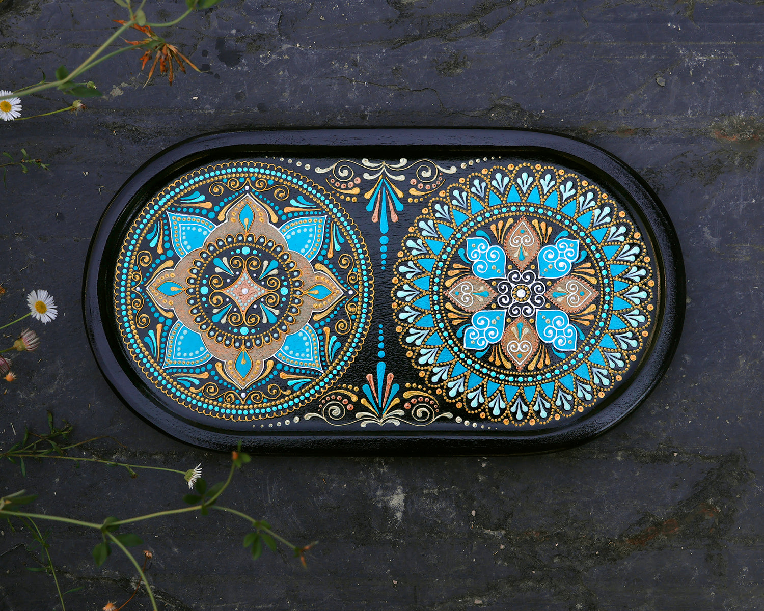 Small oval wooden tray hand-painted with mandala. Moroccan tray for coffee table. Top view on the dark stone background.