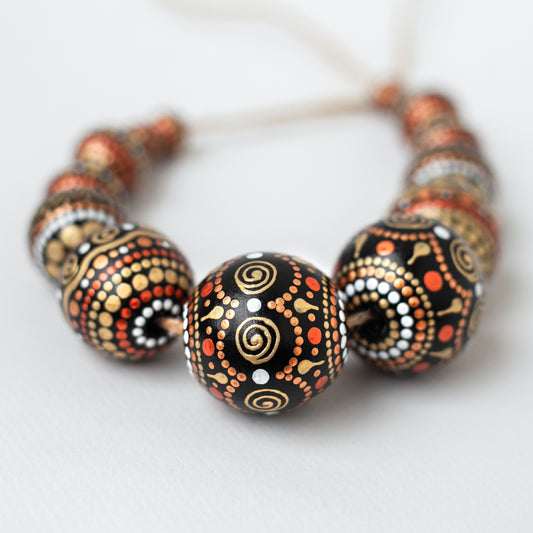 Wooden round beads collected in a garland, close-up view. Hand-painted beads in african style, gold and copper colors.