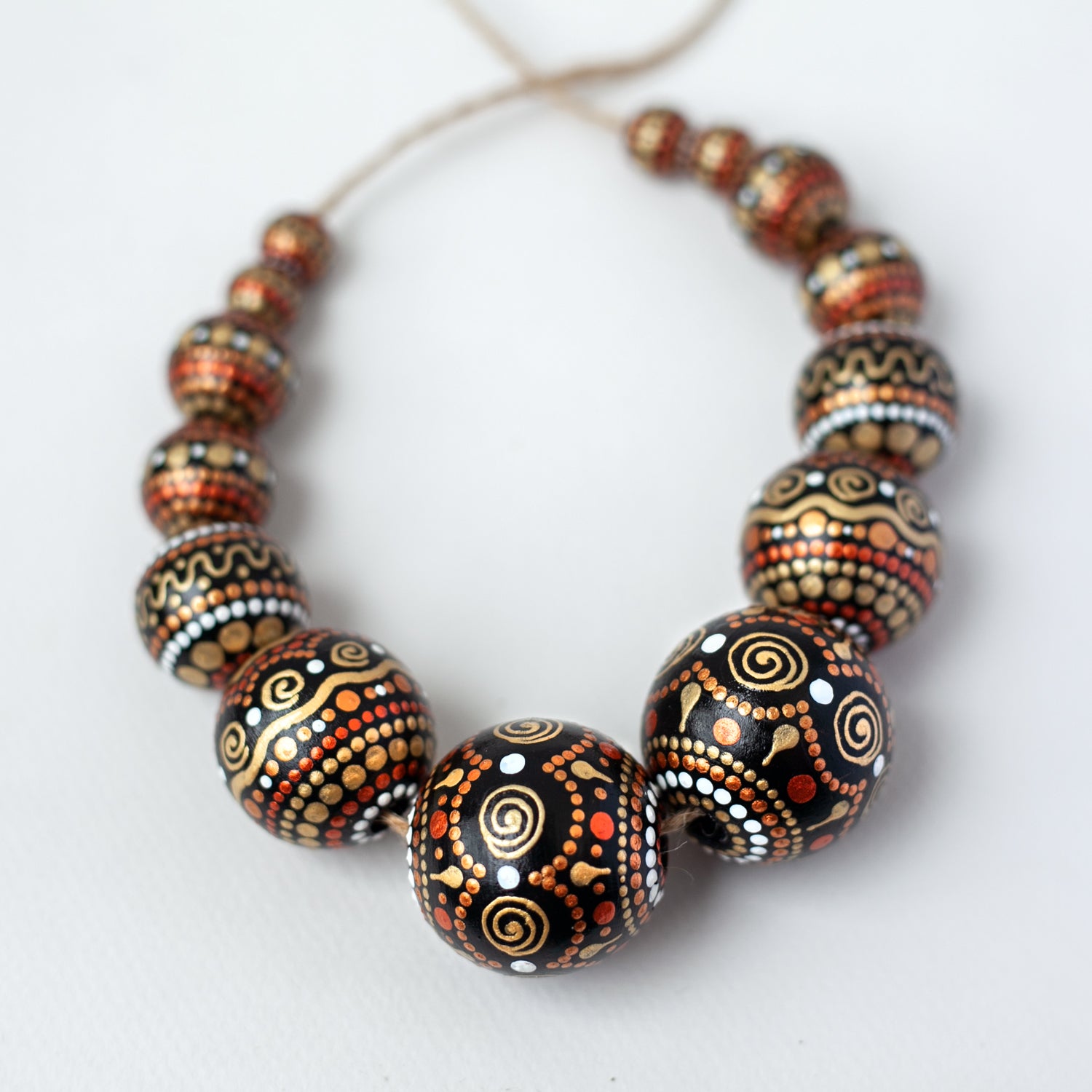 Wooden round beads collected in a garland, view from the top. Hand-painted beads in african style, gold and copper colors.
