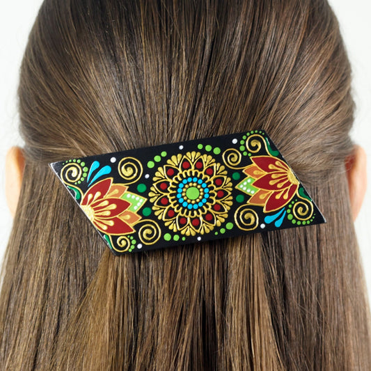 Close-up of dark hair with a colorful hand-painted wooden barrette clipped in, folk floral design.