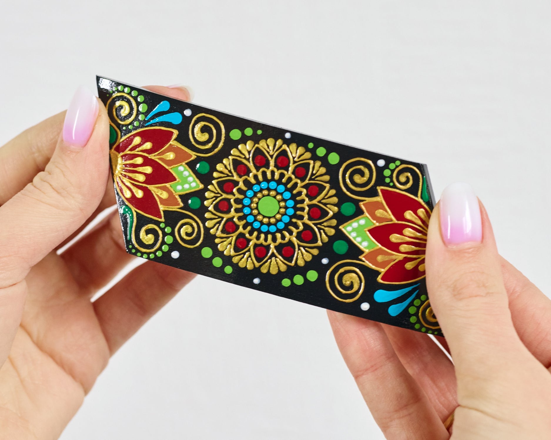 Women's hands holding wooden folk floral hair barrette