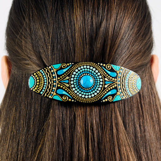 Close-up of dark hair with a colorful hand-painted wooden barrette clipped in, turquoise blue design.