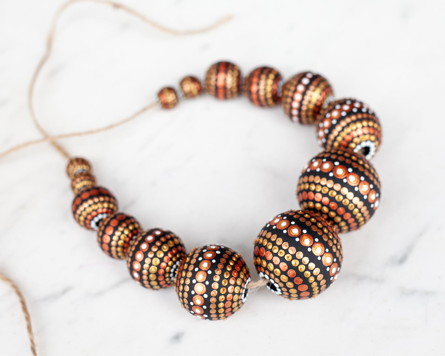 Wooden round beads collected in a garland, view from the top. Hand-painted beads in african style, gold and copper colors.