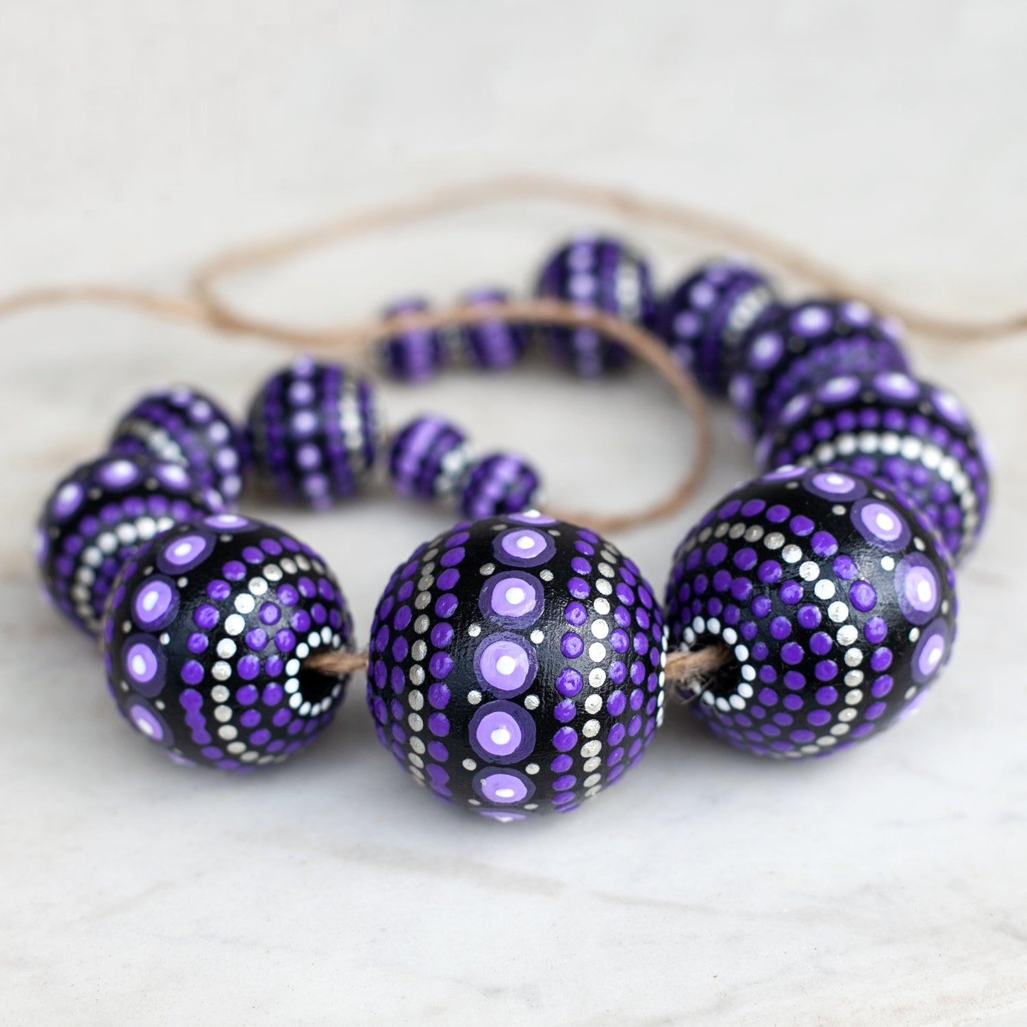 Purple round beads collected in a garland, close-up view. Hand-painted wooden beads for crafting.