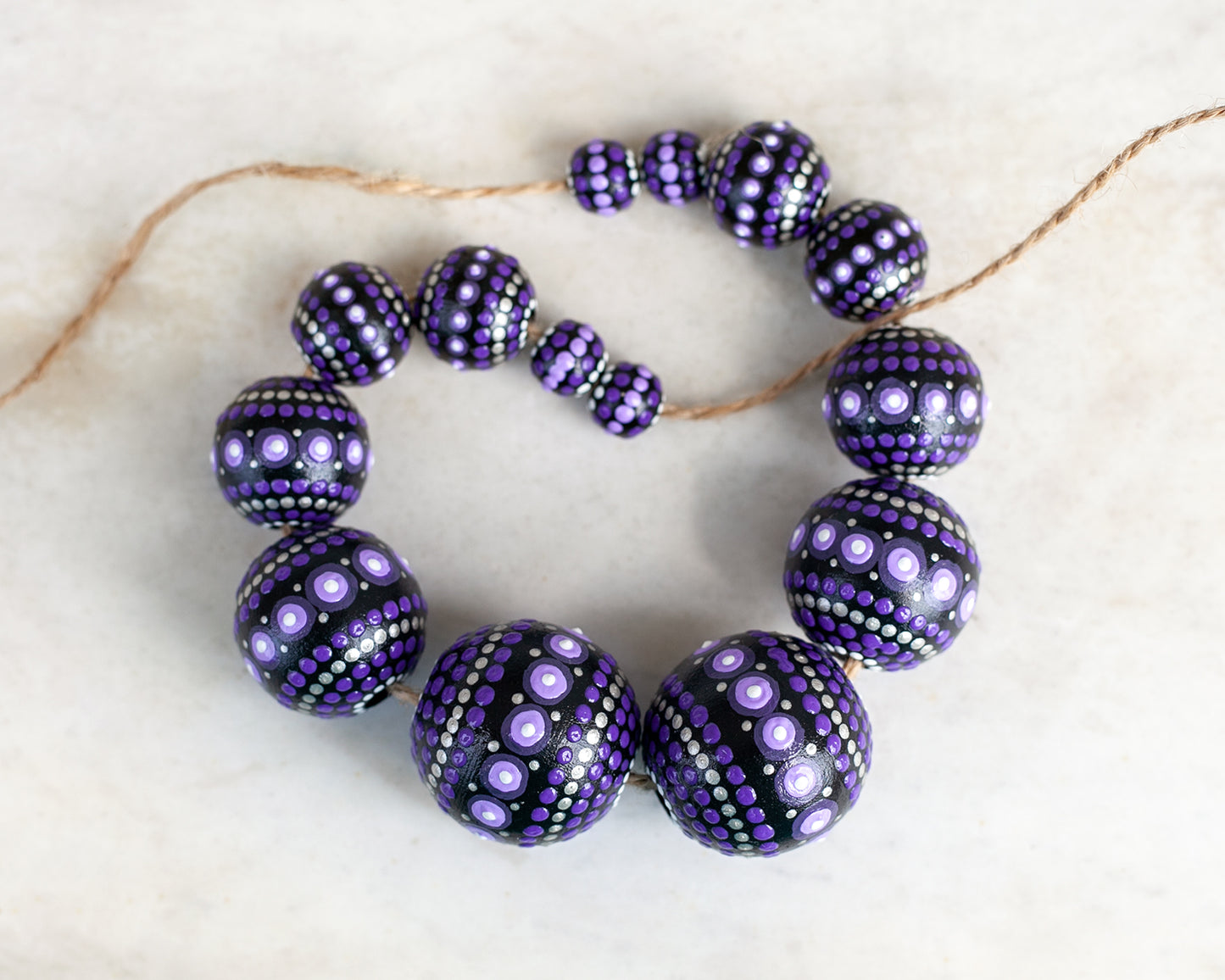 Purple round beads collected in a garland, close-up view. Hand-painted wooden beads for crafting.