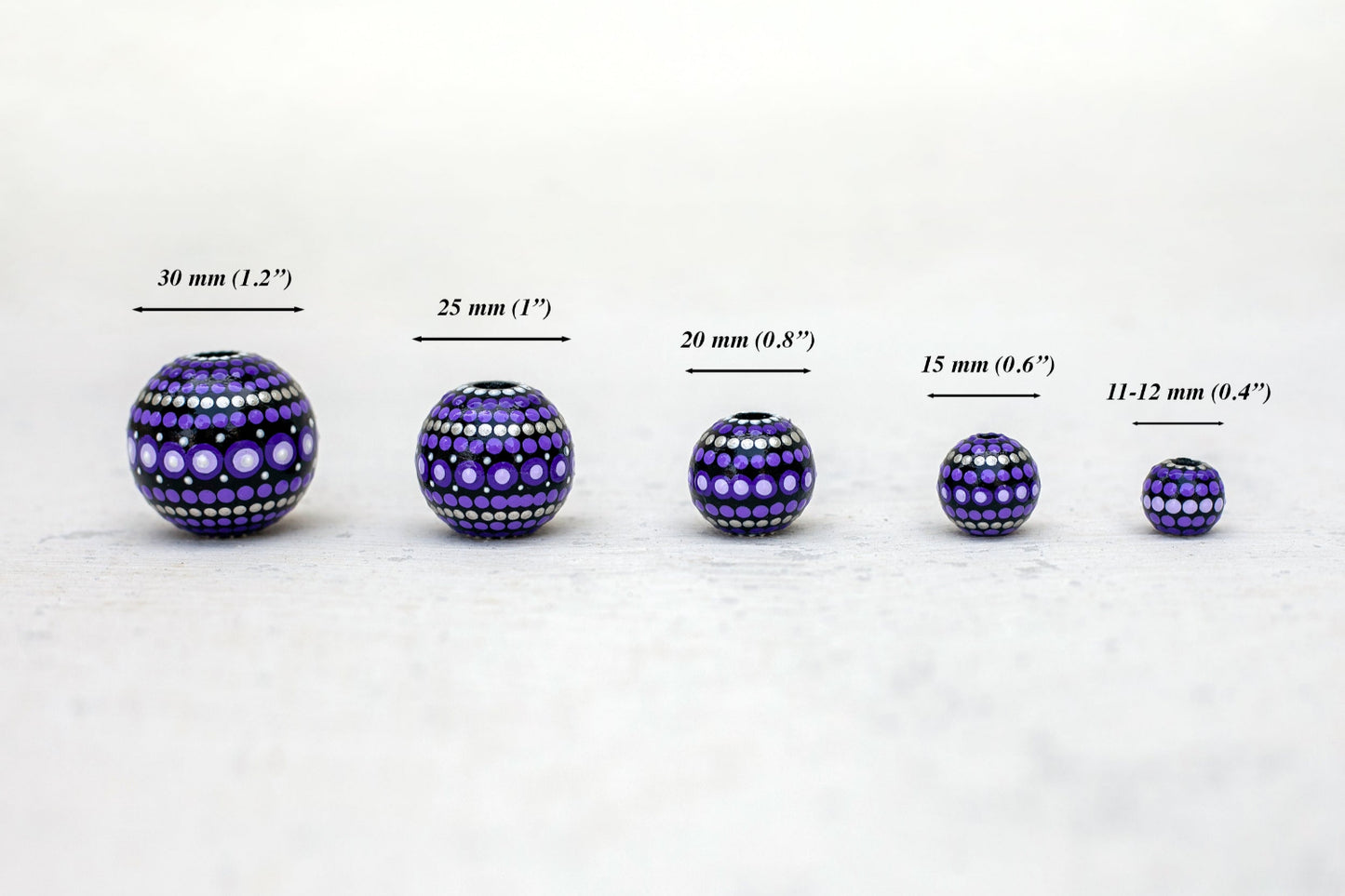 Wooden round beads in a row to show different sizes. Hand-painted beads in african style, purple violet colors.