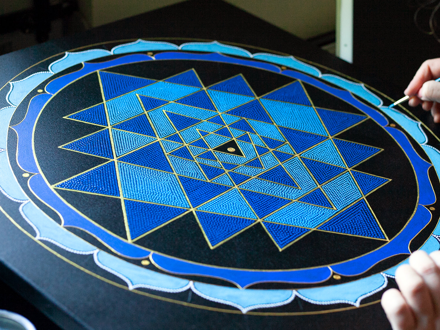 Painting process of the Shri Yantra showing, fine details and dots, close-up view, canvas on the table.