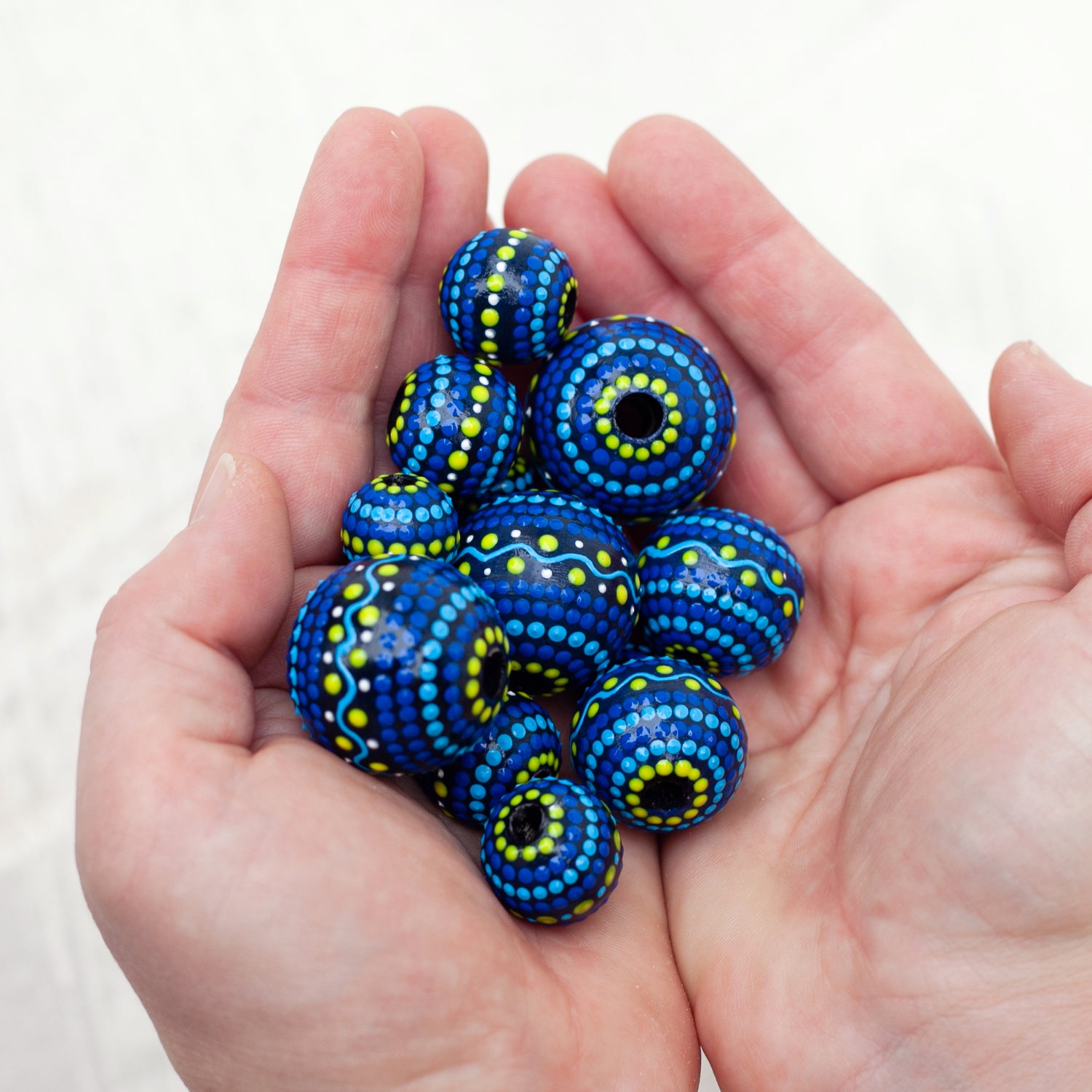 Wooden large round beads holding in  hands. Hand-painted wooden beads in folk style, blue and yellow colors.