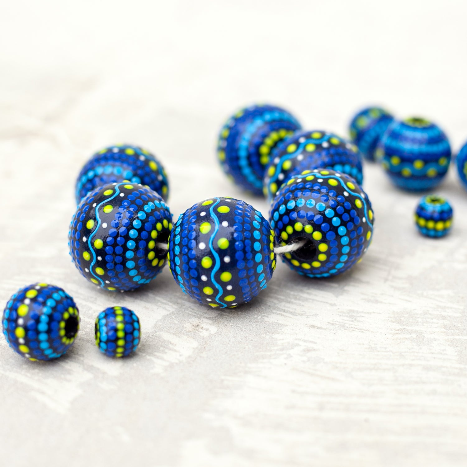 Large and small round  beads spread on the table, wooden hand-painted beads  ukrainian style. Blue and yellow colors, close-up view