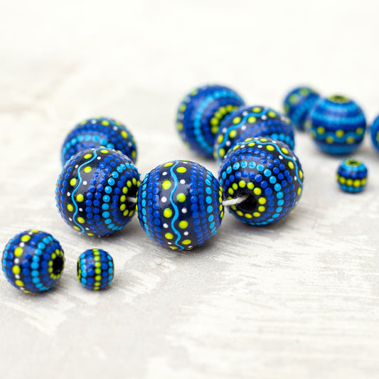 Large and small round  beads spread on the table, wooden hand-painted beads  ukrainian style. Blue and yellow colors, close-up view