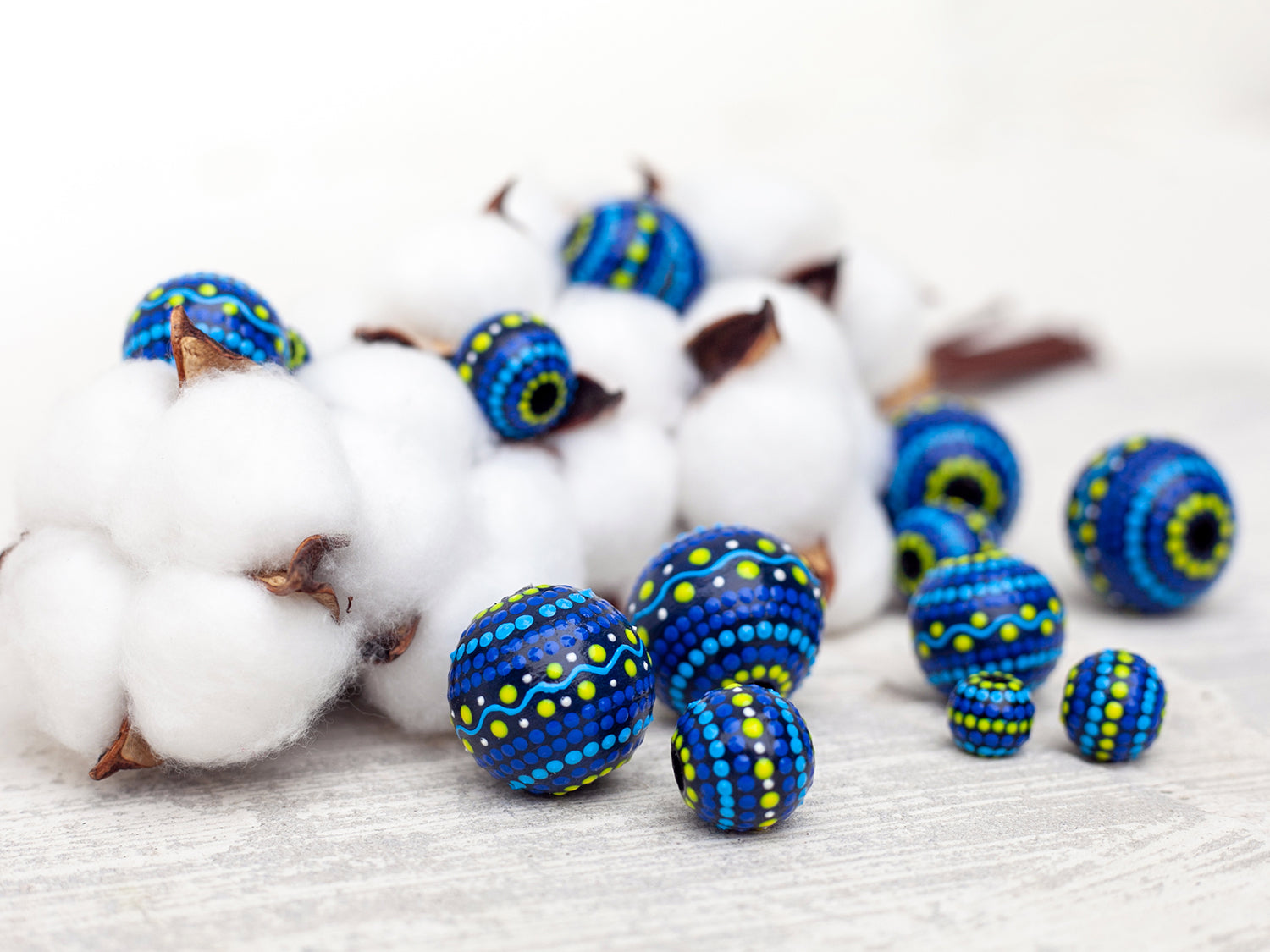 Large and small round  beads, wooden hand-painted beads. Photo composition with natural linen flowers. Blue and yellow colors, close-up view