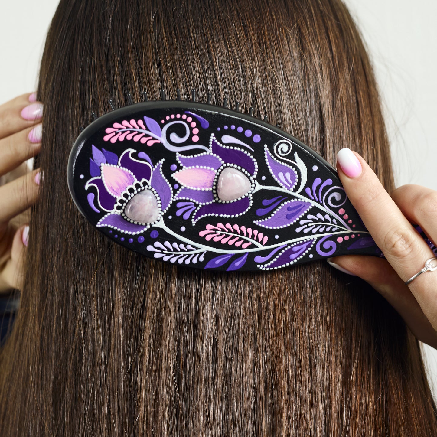 Woman using a decorative wooden purple hairbrush on her hair
