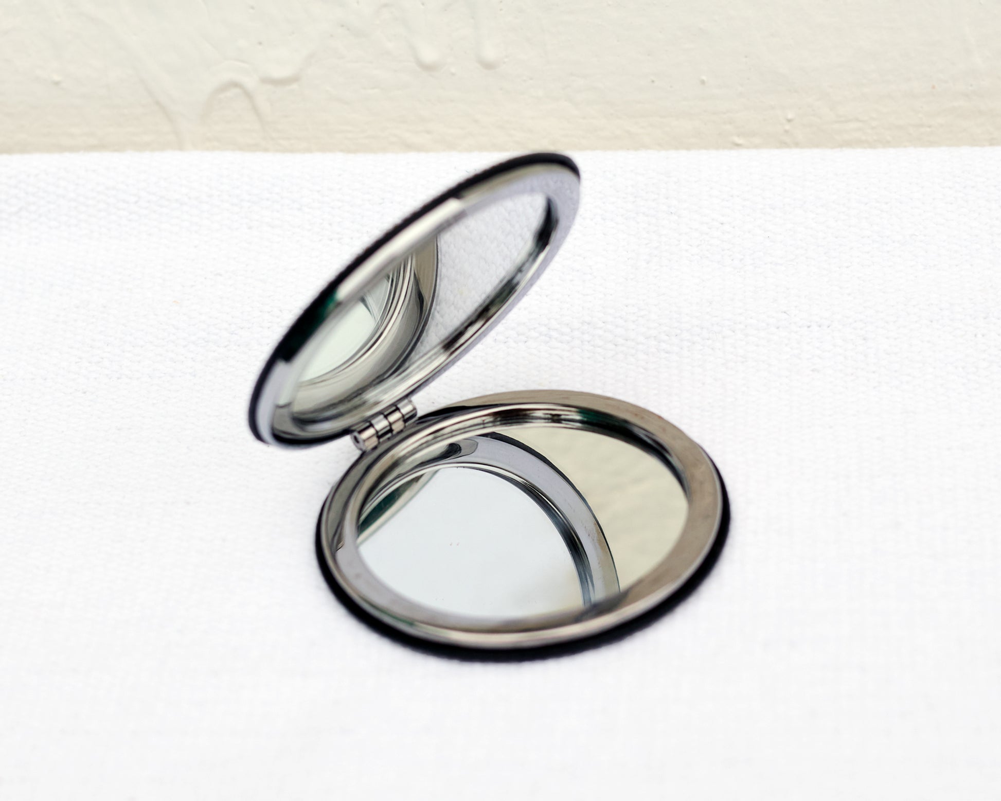 Compact mirror on a white surface with a light beige background