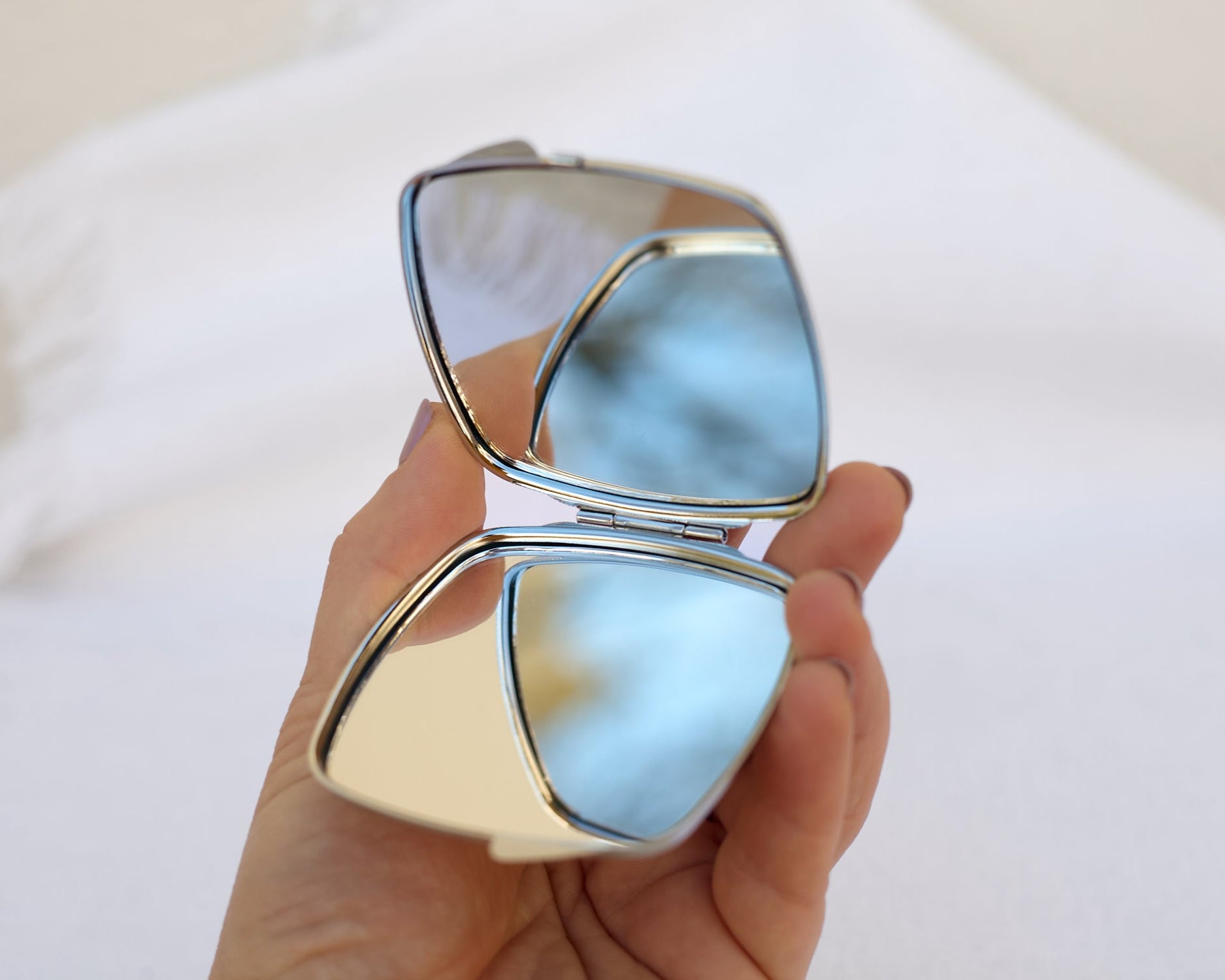 Hand holding an opened compact mirror