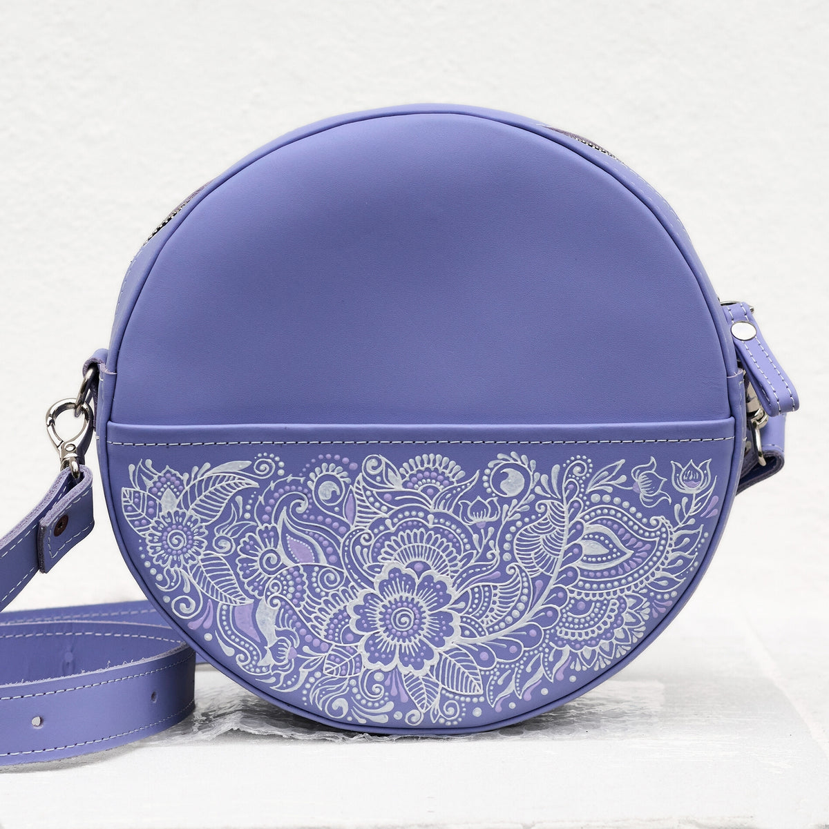 Purple round handbag with white floral patterns on a light gray background