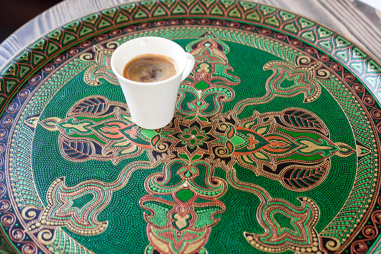 Close-up view of the green serving tray hand-painted in fantasy style. Coffee cup stands on it.