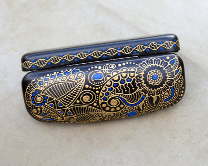 Hardshell case for glasses, hand-painted with blue and gold mehndi design. View from the top, the case is open.