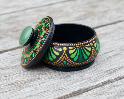 Decorative wooden hand-painted green box with natural stone on the lid on a wooden surface