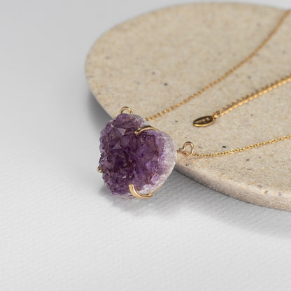 amethyst druzy heart necklace with a gold chain on a stone plate