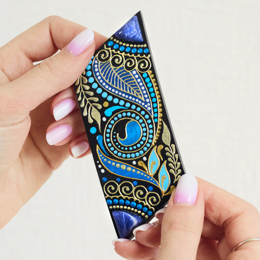 Women's hands holding wooden hair barrette painted in blue