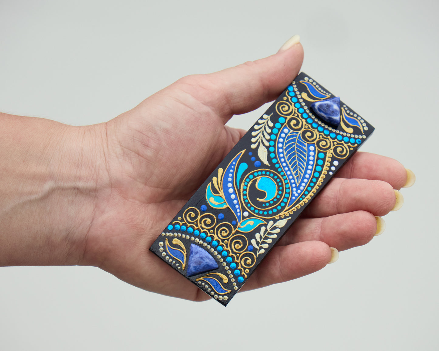 Hand holding wooden hair barrette painted in blue