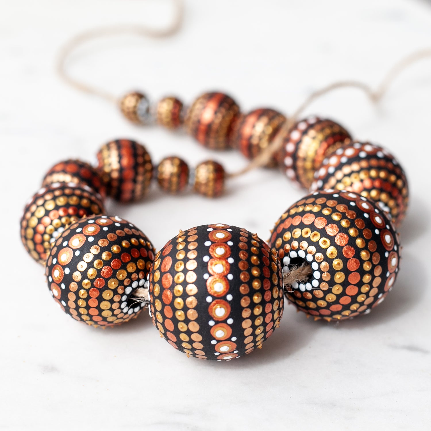 Wooden round beads collected in a garland, close-up view. Hand-painted beads in african style, gold and copper colors.