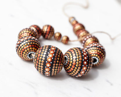 Wooden round beads collected in a garland, close-up view. Hand-painted beads in african style, gold and copper colors.
