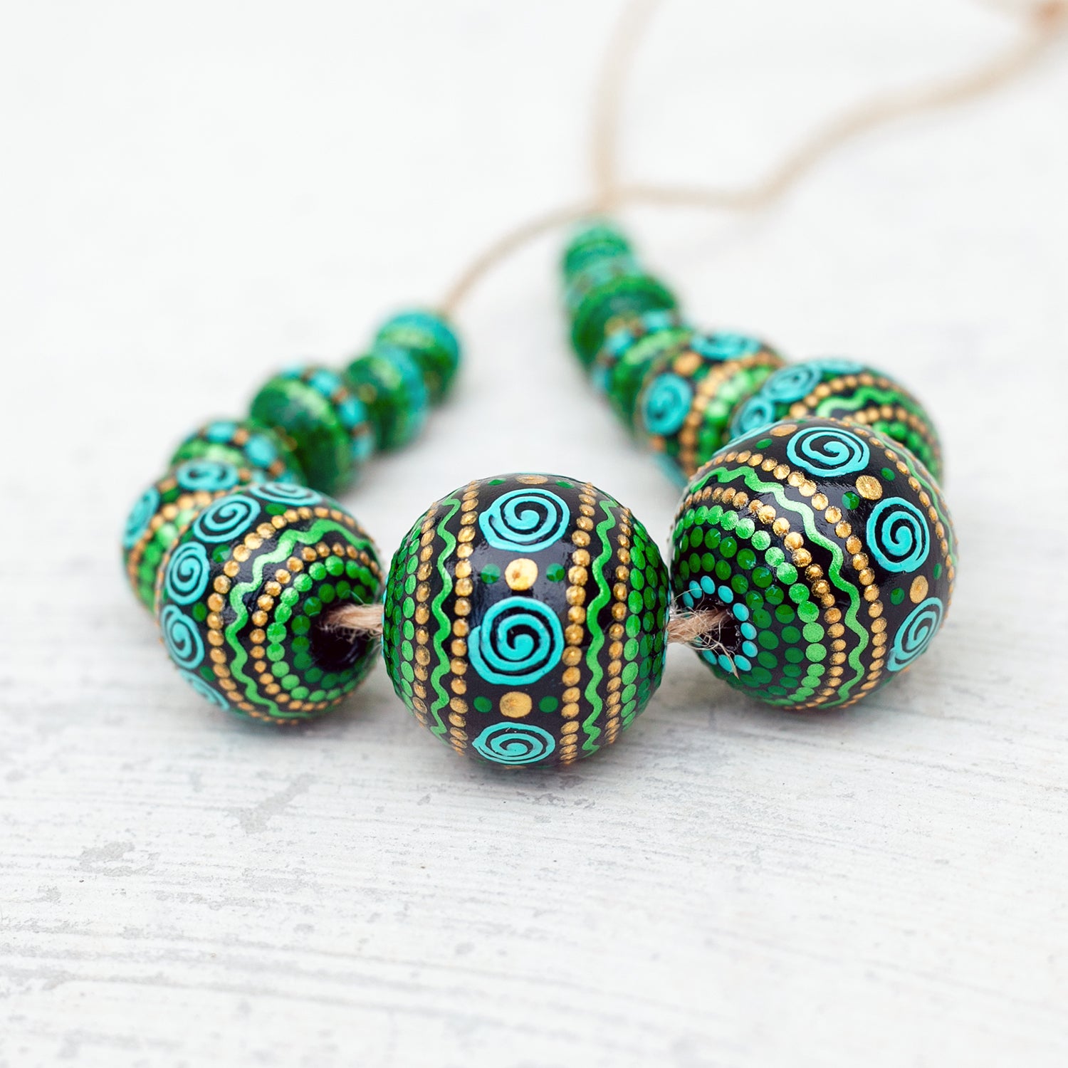 Wooden round beads collected in a garland, close-up view. Hand-painted beads in african style, green, mint and gold colors.
