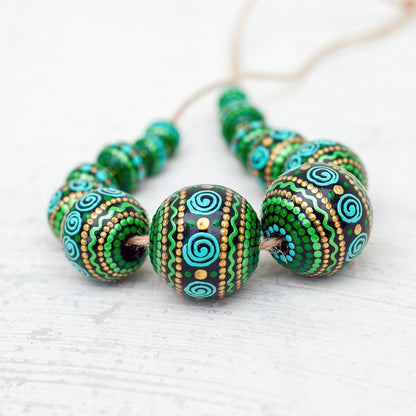 Wooden round beads collected in a garland, close-up view. Hand-painted beads in african style, green, mint and gold colors.