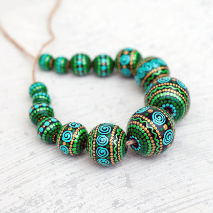 Wooden round beads collected in a garland, view from the side. Hand-painted beads in african style, green, mint and gold colors.