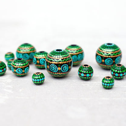 Large and small round  beads spread on the table, wooden hand-painted beads in african style. Green, mint and gold colors, close-up view