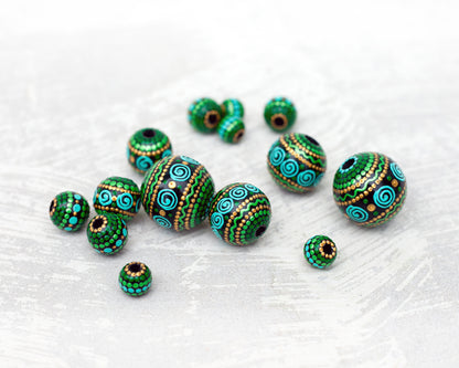 Large and small round  beads spread on the table, wooden hand-painted beads in african style. Green, mint and gold colors, close-up view
