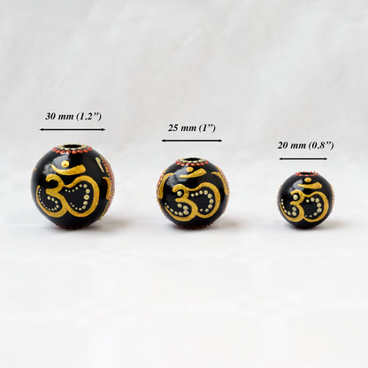 Wooden round beads in a row to show different sizes. Hand-painted large beads with the Om symbol.