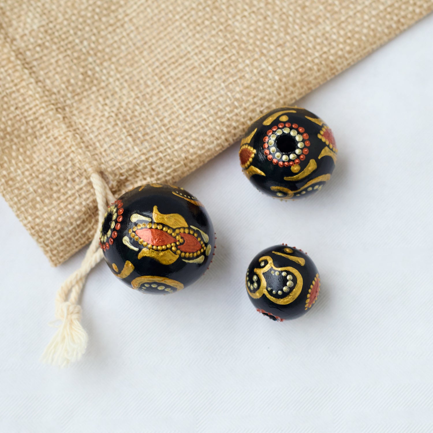 Three hand-painted wooden beads featuring the gold Om symbol on a white background. Close-up view