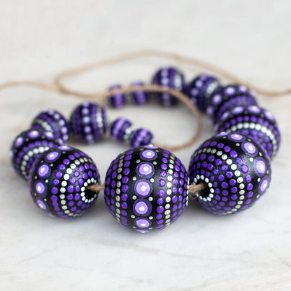 Purple round beads collected in a garland, close-up view. Hand-painted wooden beads for crafting.
