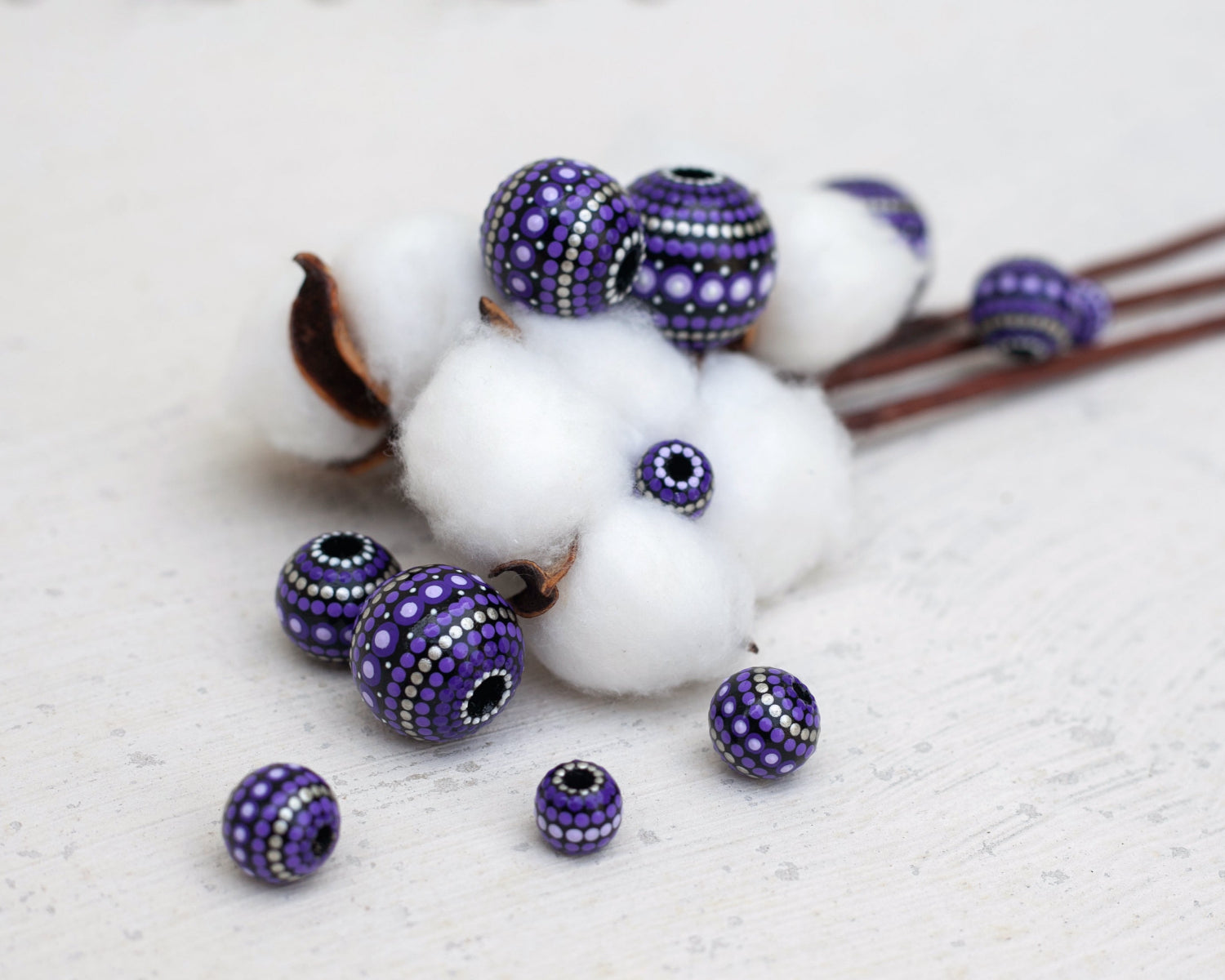 Large and small round  beads, wooden hand-painted beads in african style. Photo composition with natural linen flowers. Purple beads, close-up view