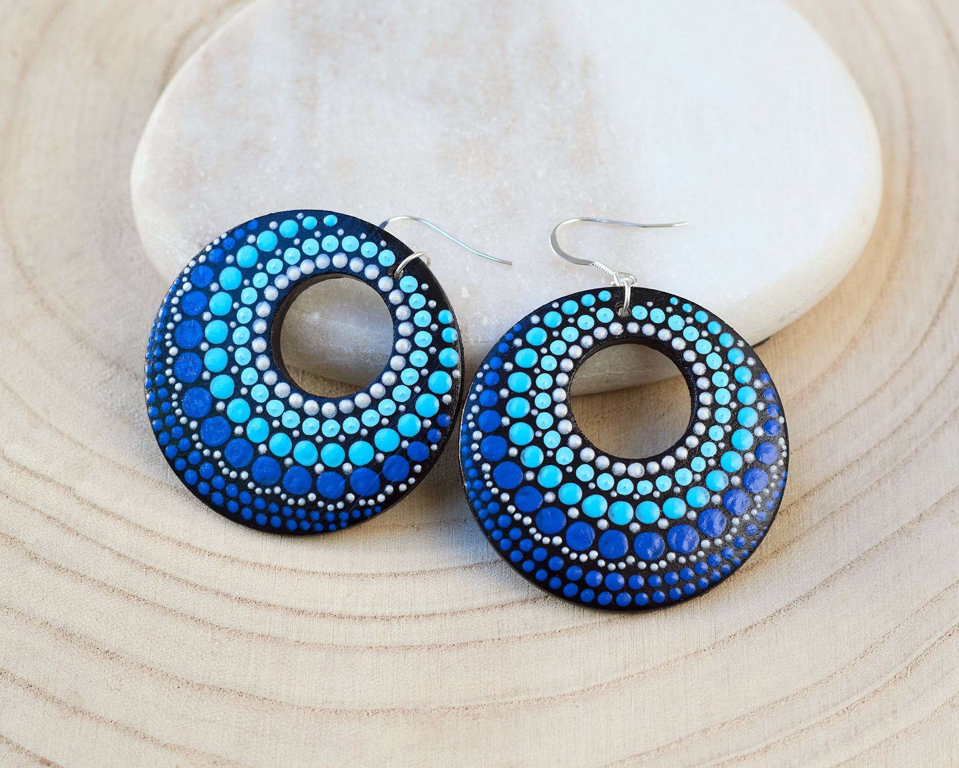 Blue round dot-patterned earrings on a light wood surface