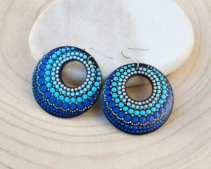 Blue round dot-patterned earrings on a light wood surface