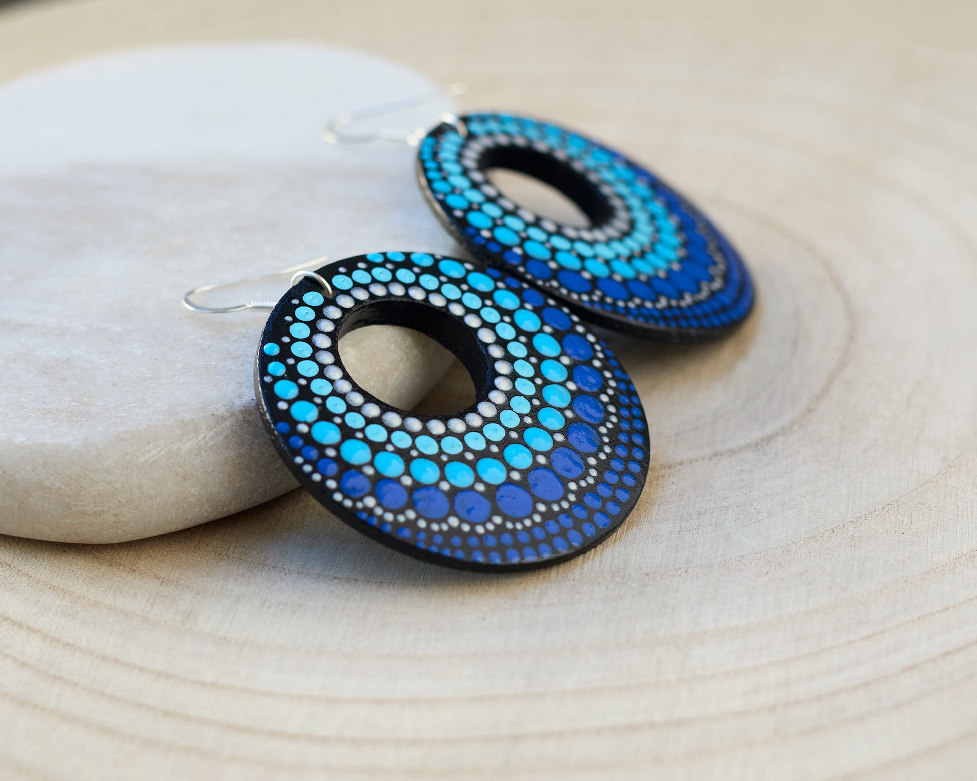 Blue dots circular earrings on a light wooden surface