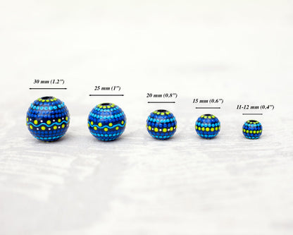 Wooden round beads in a row to show different sizes. Blue hand-painted beads.