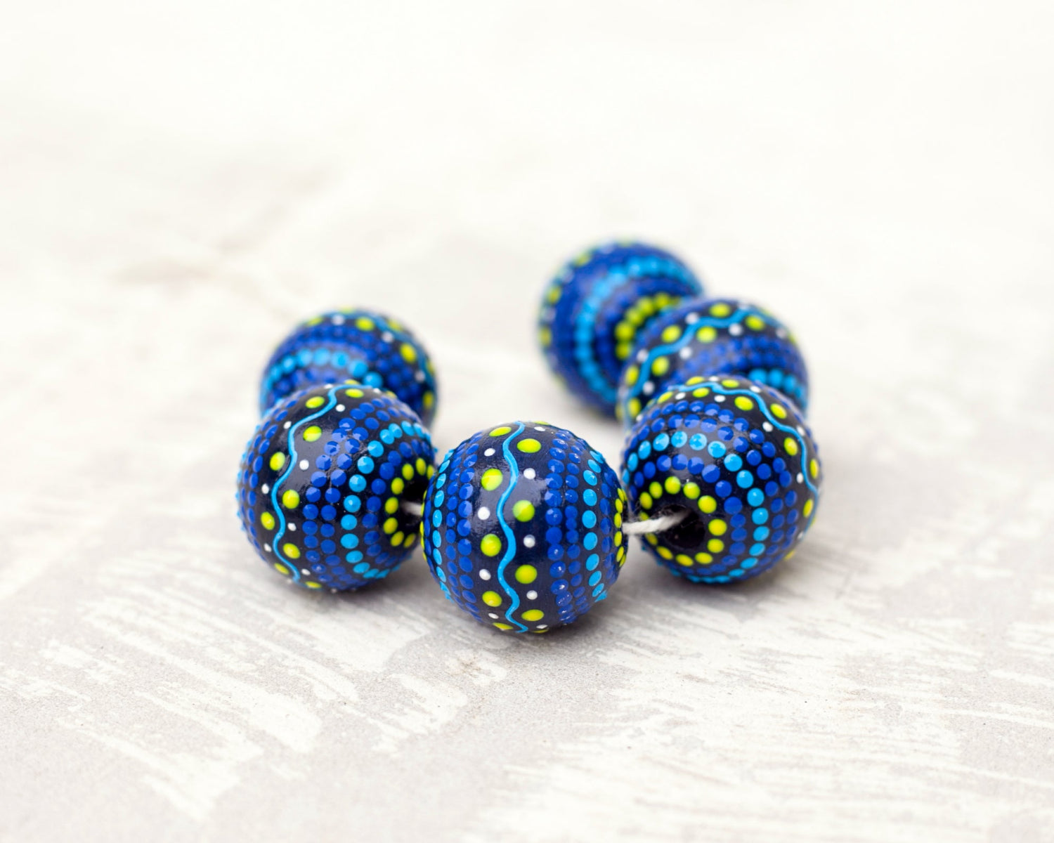 Wooden round beads collected in a garland, close-up view. Hand-painted beads in folk style, blue and yellow colors.