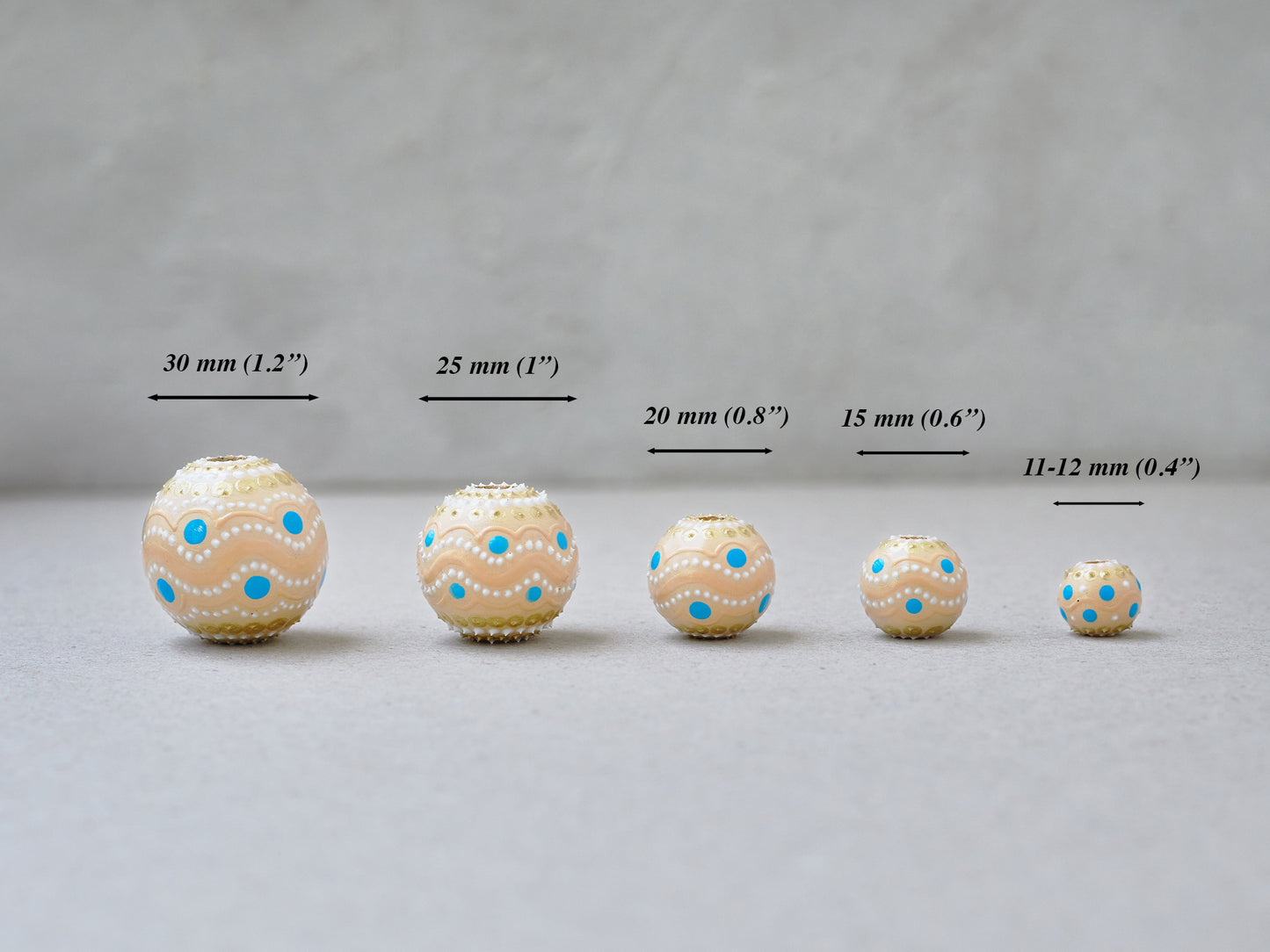 Wooden round beads in a row to show different sizes. Hand-painted beige boho beads lined up in a row