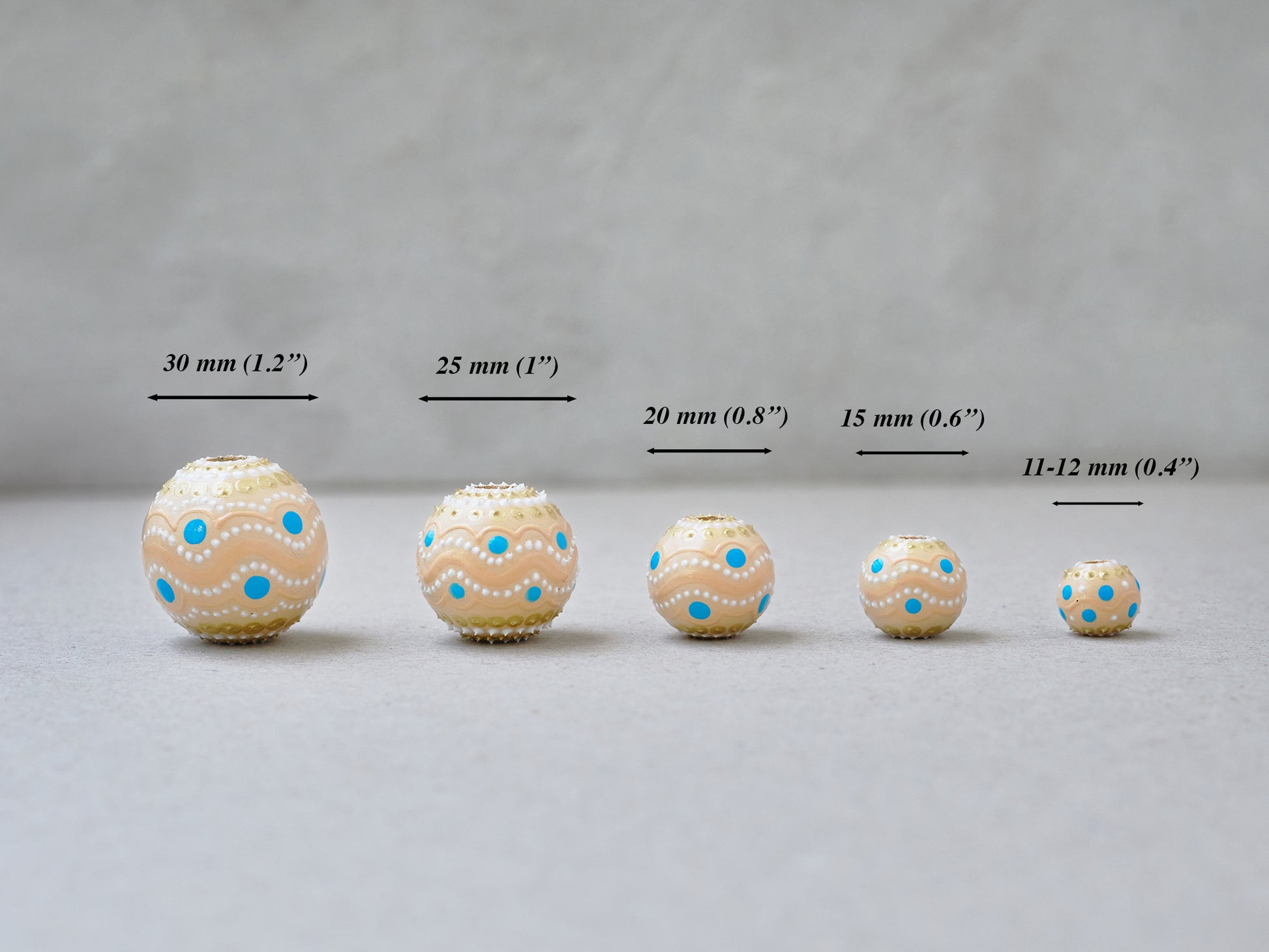 Wooden round beads in a row to show different sizes. Hand-painted beige boho beads lined up in a row