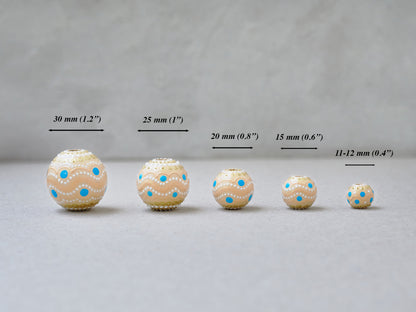 Wooden round beads in a row to show different sizes. Hand-painted beige boho beads lined up in a row