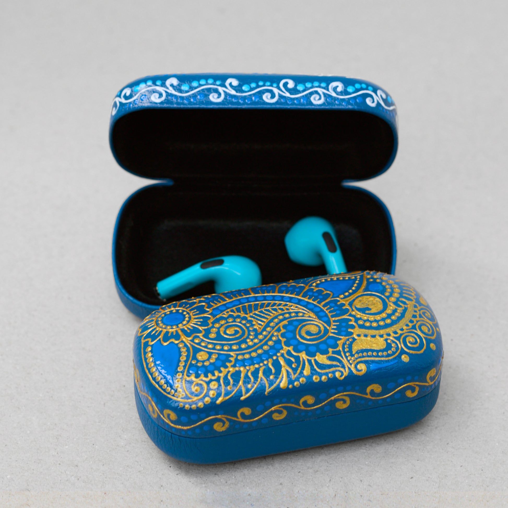 Two blue mehndi design earphones cases on gray background, one is open with earbuds inside